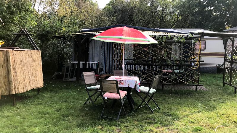 Tisch mit Schirm und drei Stühlen im Garten