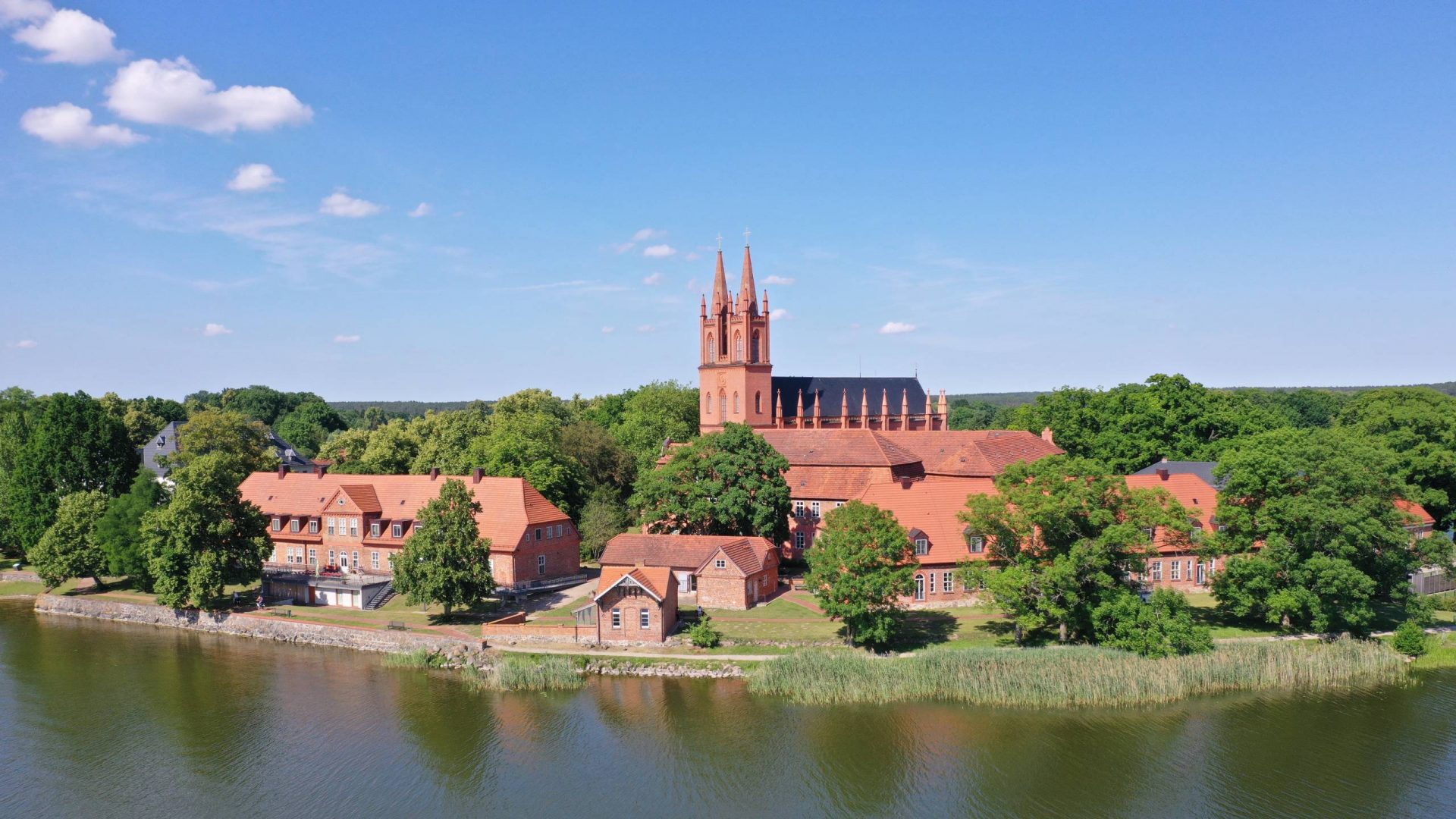 Klosterkirche Dobbertin mit zwei Kirchtürmen und weiteren Gebäuden am See